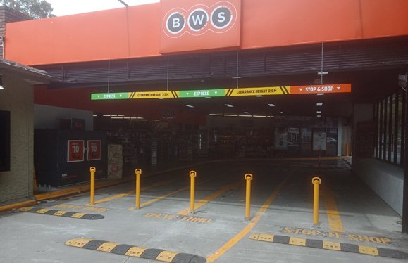 Yellow removable bollards across the drive-through entry at BWS Olinda Creek
