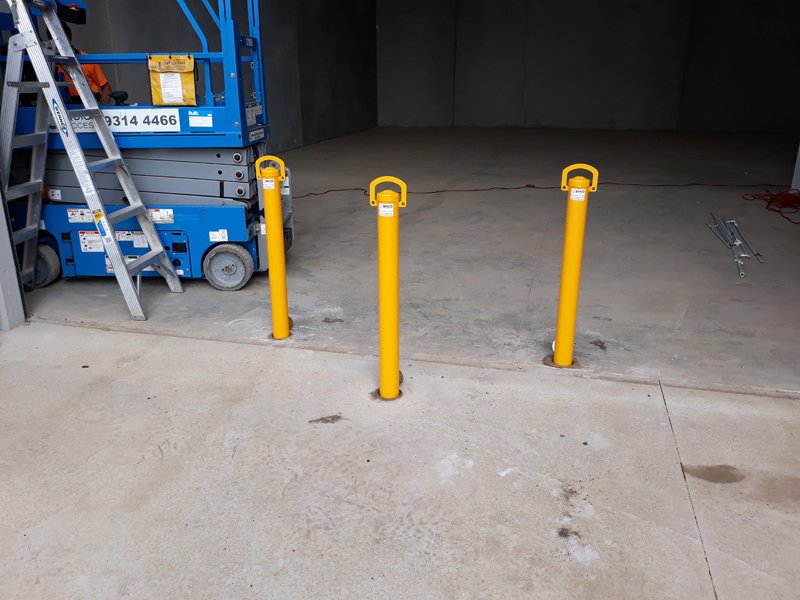 Three removable bollards across a warehouse entry