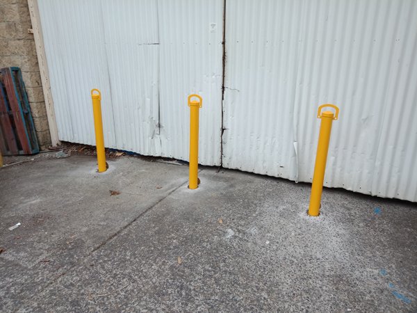 Three removable bollards in front of corrugated shed doors at York on Lilydale
