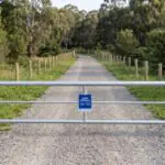 Galvanised steel access gate across a gravel track, built to Melbourne Water specification