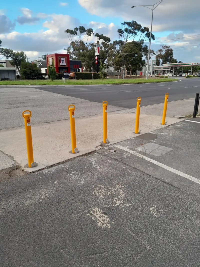 A row of yellow removable bollards along a car yard frontage