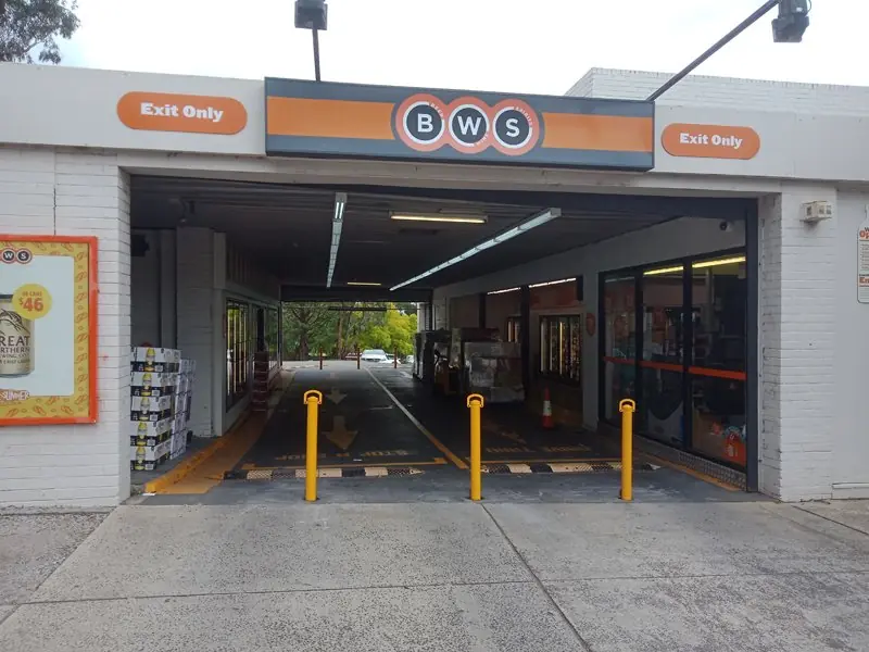 Yellow removable bollards at the drive-through entrance of BWS Eltham