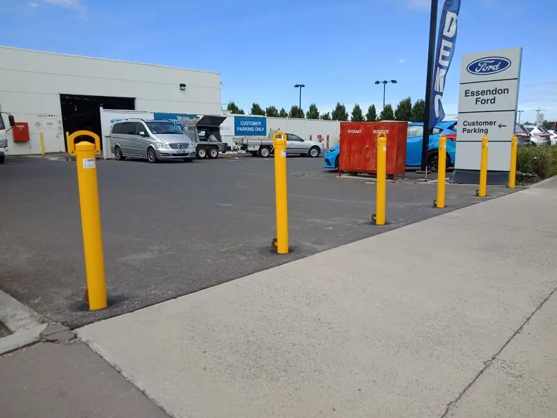 Yellow removable bollards protecting the customer car park at Essendon Ford