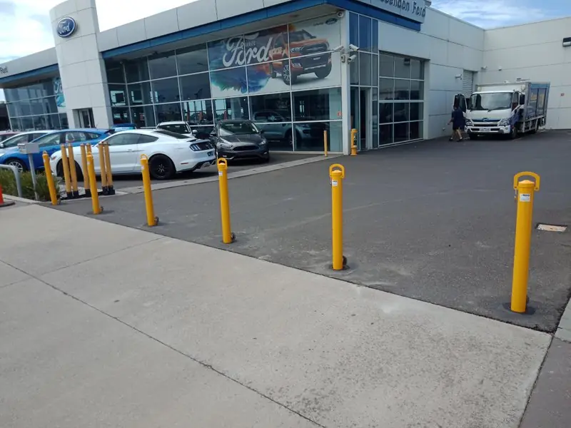 Row of yellow removable bollards along the car yard frontage at Essendon Ford
