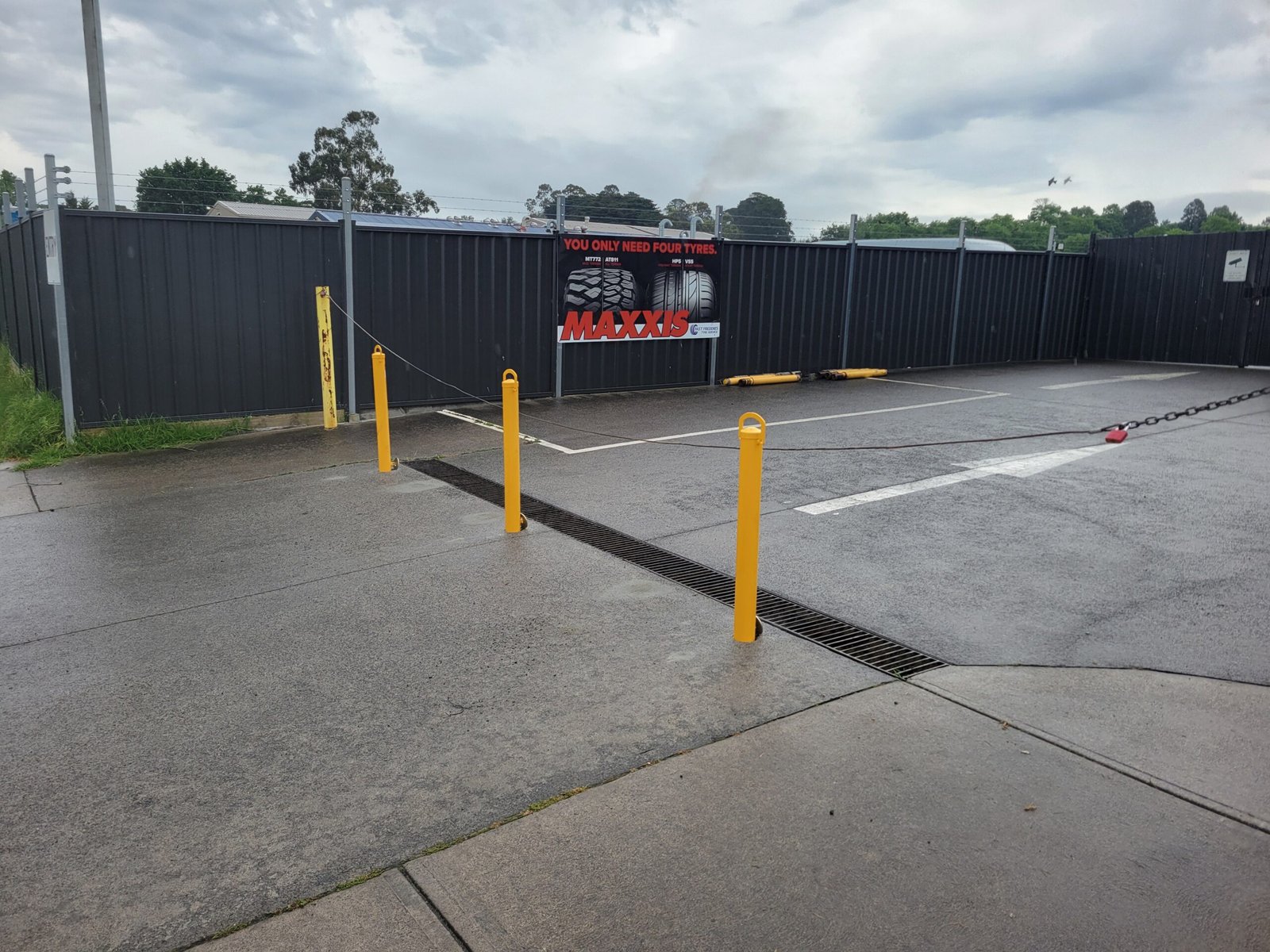 Yellow removable bollards with lifting handles beside the drainage channel at the Healesville workshop.