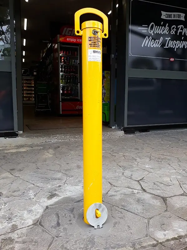 A key-lockable removable bollard in front of a FoodWorks shopfront