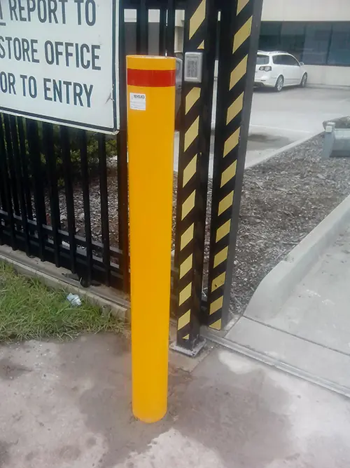 Yellow permanent bollards beside a driveway gate, Laverton