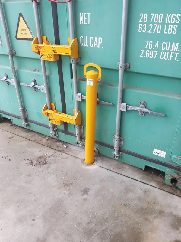 A removable bollard locked in front of the doors of a shipping container