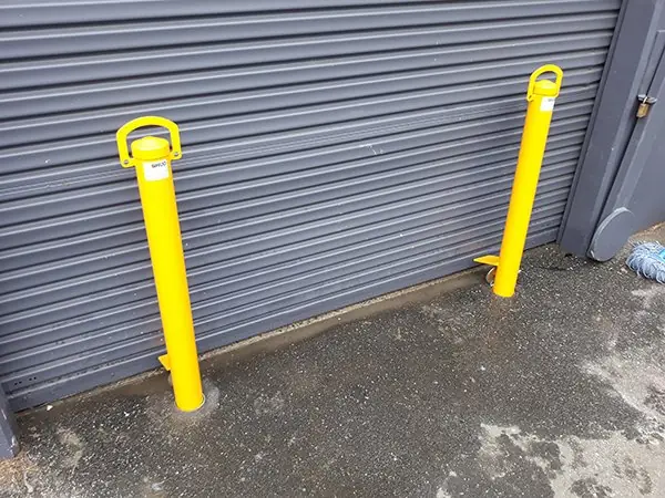 Two removable bollards in front of a grey roller door